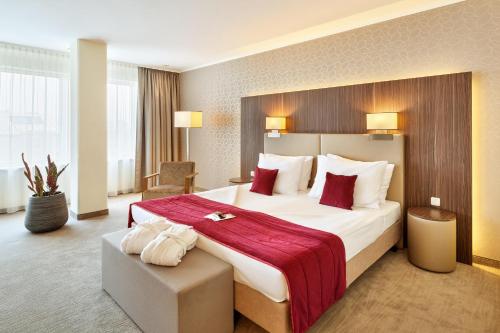 Cette chambre comprend un grand lit avec une couverture rouge. dans l'établissement Hotel Schillerpark Linz, a member of Radisson Individuals, à Linz