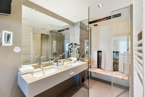 a bathroom with two sinks and a glass shower at Hotel Schillerpark Linz, a member of Radisson Individuals in Linz