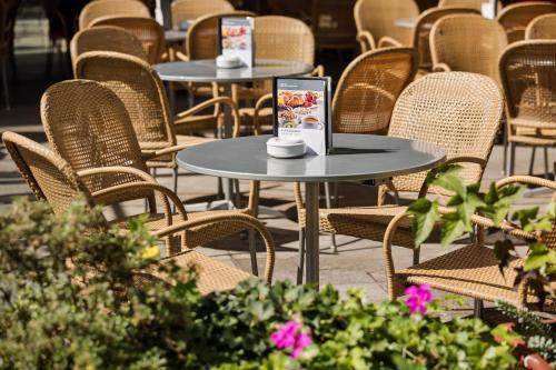 a row of tables and chairs with pink flowers at Hotel Schillerpark Linz, a member of Radisson Individuals in Linz