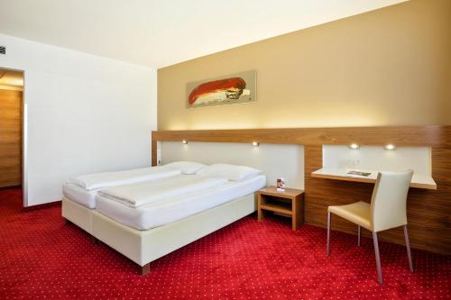 Schlafzimmer mit einem großen weißen Bett und einem Schreibtisch in der Unterkunft Austria Trend Hotel Anatol Wien in Wien