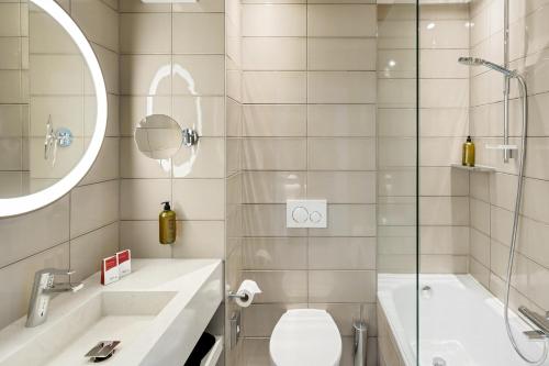 a bathroom with a tub and a toilet and a sink at Austria Trend Hotel Bosei Wien in Vienna