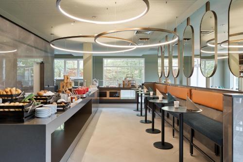 a restaurant with a long counter with tables and chairs at Austria Trend Hotel Bosei Wien in Vienna