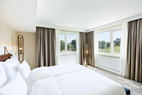 a bedroom with a white bed and two windows at Austria Trend Hotel Bosei Wien in Vienna