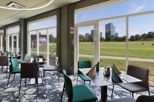 a dining room with tables and chairs and windows at Austria Trend Hotel Bosei Wien in Vienna
