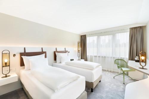 a hotel room with two beds and a desk at Austria Trend Hotel Bosei Wien in Vienna