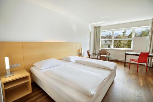 a bedroom with a large white bed and a desk at Austria Trend Hotel Congress Innsbruck in Innsbruck