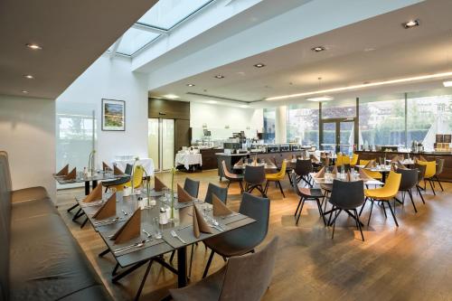 a dining room with tables and chairs and windows at Austria Trend Hotel Congress Innsbruck in Innsbruck