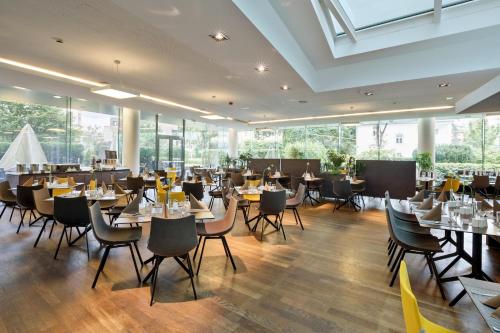 a dining room with tables and chairs and windows at Austria Trend Hotel Congress Innsbruck in Innsbruck