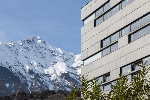 a building with a view of a snow covered mountain at Austria Trend Hotel Congress Innsbruck in Innsbruck