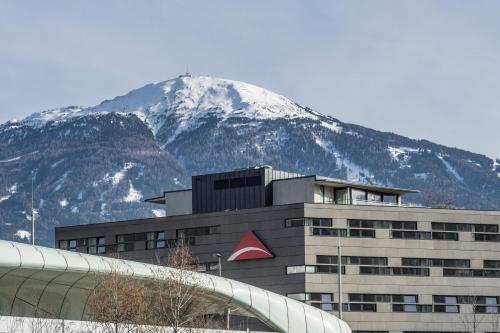 a building with a snow covered mountain in the background at Austria Trend Hotel Congress Innsbruck in Innsbruck