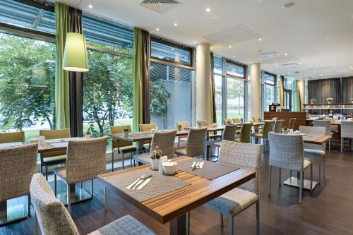 um restaurante com mesas, cadeiras e janelas em Austria Trend Hotel Doppio Wien em Viena