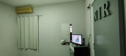 a living room with a television and a mirror at Acomodações no Jardim Tropical em Rondonópolis in Rondonópolis