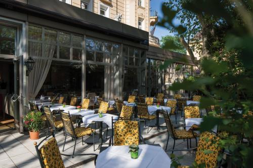 eine Reihe von Tischen und Stühlen auf einer Terrasse in der Unterkunft Austria Trend Parkhotel Schönbrunn Wien in Wien