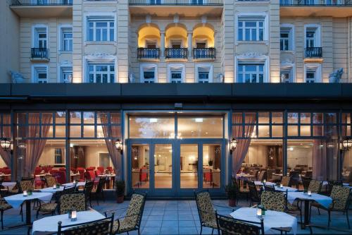 a restaurant with tables and chairs in front of a building at Austria Trend Parkhotel Schönbrunn Wien in Vienna