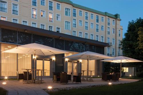 a patio with tables and umbrellas in front of a building at Austria Trend Parkhotel Schönbrunn Wien in Vienna