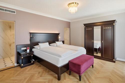 a bedroom with a large bed and a purple stool at Austria Trend Parkhotel Schönbrunn Wien in Vienna