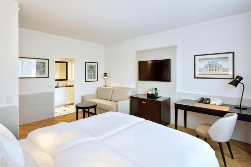 a white hotel room with a bed and a desk at Austria Trend Parkhotel Schönbrunn Wien in Vienna