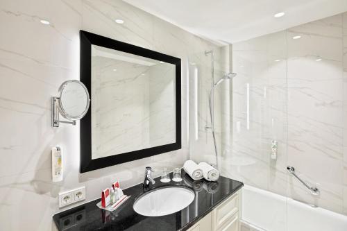 a bathroom with a sink and a shower and a mirror at Austria Trend Parkhotel Schönbrunn Wien in Vienna