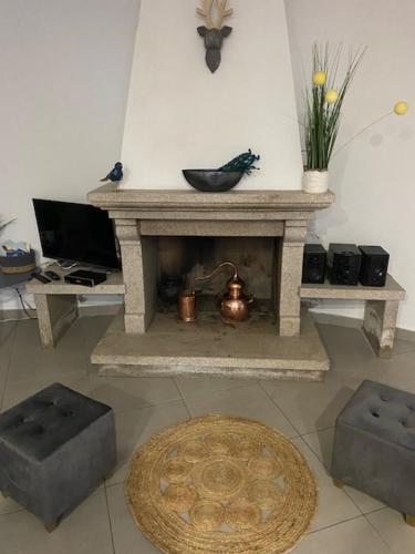 a living room with a stone fireplace with two stools at Casa da Clemencia in Cardeal
