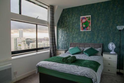 - une chambre avec un lit aux murs verts et une fenêtre dans l'établissement Manchester City Centre Apartment, Skyline View, à Manchester