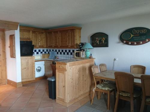 une cuisine avec des armoires en bois et une table avec des chaises dans l'établissement Duplex 4 pièces au pied des pistes avec parking et animaux acceptés - FR-1-411-599, à Bourg-Saint-Maurice