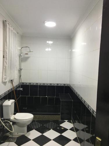 uma casa de banho com WC e azulejos pretos e brancos. em Gaser resident em Cidade 6 de Outubro