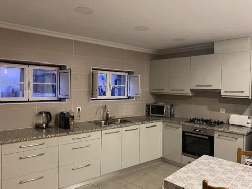 a kitchen with white cabinets and a counter top at Casa da Clemencia in Cardeal
