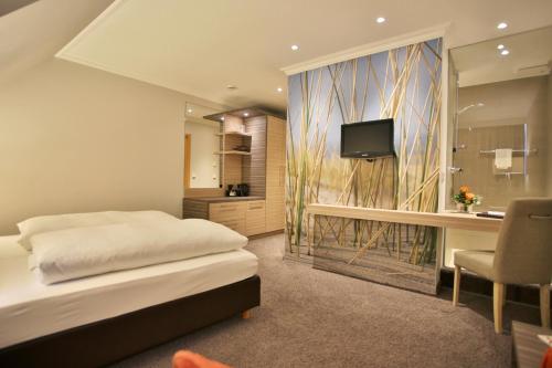 a bedroom with a bed and a desk and a television at Boutiquehotel Myn Utspann in Husum