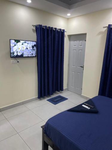 um quarto com cortinas azuis e uma televisão e uma cama em Uniro Rooms & Packages em Cochin