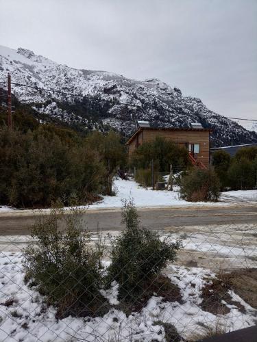 uma cerca em frente a uma casa com uma montanha coberta de neve em Tiny house Bariloche em San Carlos de Bariloche