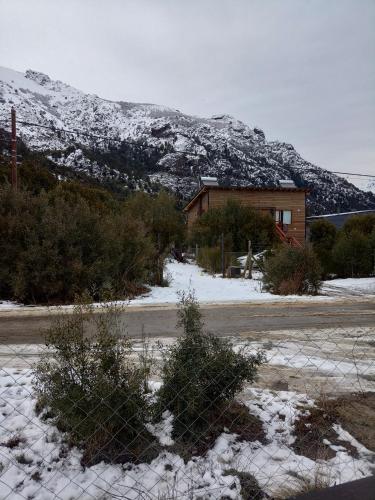 a fence in front of a house with a snow covered mountain at Tiny house Bariloche in San Carlos de Bariloche