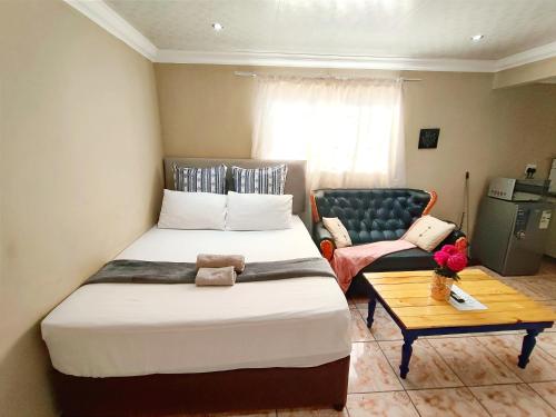 1 dormitorio con cama, sofá y mesa en Zikora en Pretoria