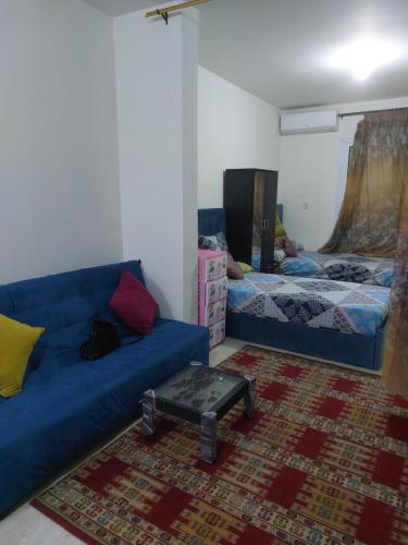 شاليه بالساحل الشمالي للايجار في العلمين: غرفة معيشة مع أريكة زرقاء وسرير