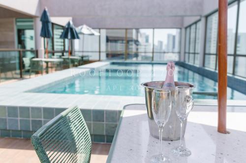 - une paire de verres à vin assis sur une table à côté d'une piscine dans l'établissement Flat luxo Boa Viagem Rooftop 470, à Récife