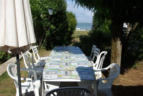 une table et des chaises avec un parasol et l'océan dans l'établissement Baignade au bout du jardin, à La Flotte