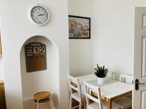 a dining room with a table and a clock on the wall at No.18 - Ground Floor apartment close to the beach in Cromer