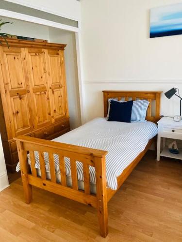 a bedroom with a wooden bed with a blue pillow at No.18 - Ground Floor apartment close to the beach in Cromer