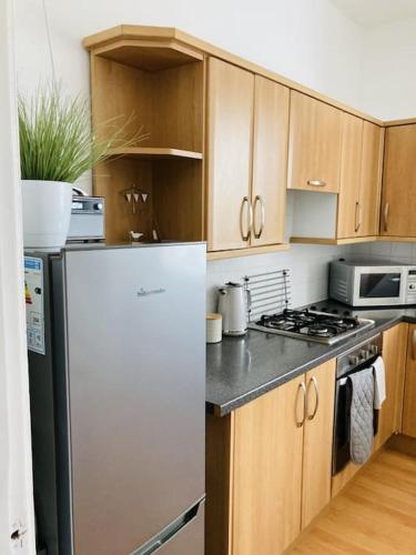 a kitchen with a white refrigerator and wooden cabinets at No.18 - Ground Floor apartment close to the beach in Cromer