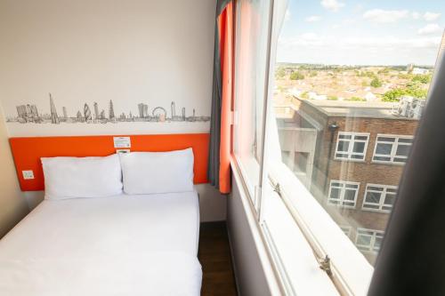 a bed in a room with a large window at easyHotel Croydon in Croydon