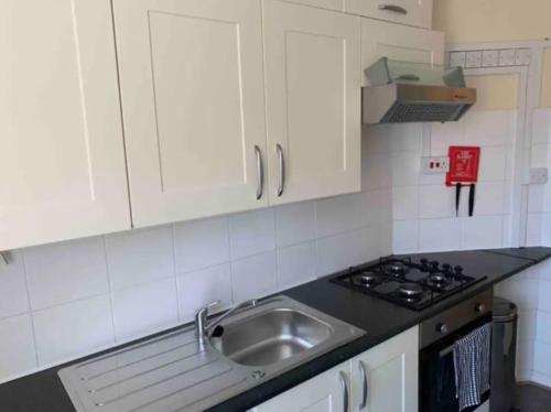 Una cocina con gabinetes blancos y un fregadero. en APlaceToStay Central London Apartment, Zone 1 NHG, en Londres
