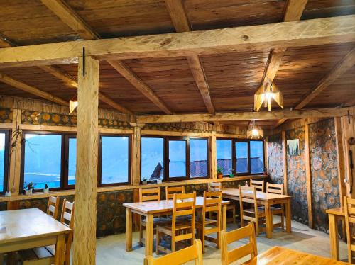 a dining room with wooden tables and chairs and windows at Panorama Bakhmaro in Bakhmaro
