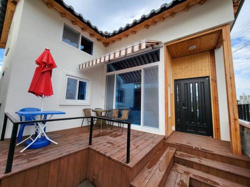 a wooden deck with a table and a red umbrella at Donghae Hanok Stay in Donghae