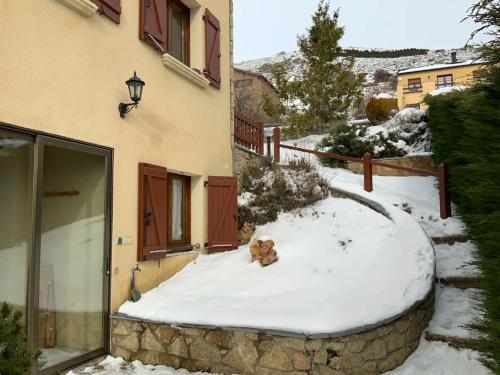 a dog laying in the snow next to a building at Appartement avec vue, jacuzzi, jardin privatif in Targassonne