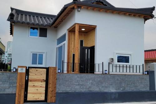 a white house with a wooden door and a fence at Donghae Hanok Stay in Donghae