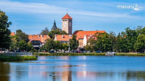 a town with a clock tower and a lake at Apartament Mazurska Natura in Szczytno