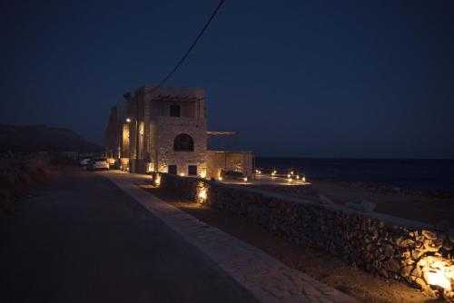 a building with lights on the beach at night at Monodendri Suites in Yerolimin