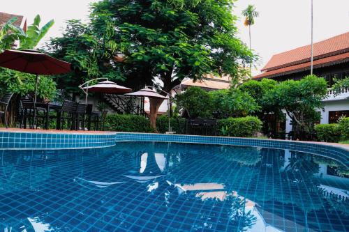 uma piscina azul com guarda-sol e árvores em Meuangluang Hotel em Luang Prabang