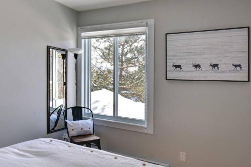 1 dormitorio con 1 cama y 2 ventanas con ciervo en la nieve en Cozy Chalet in the Mont Tremblant Ski Village en Mont-Tremblant