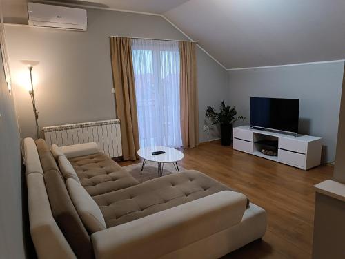 a living room with a couch and a television at Apartman Mima in Borča