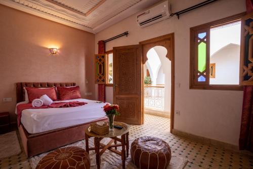 a bedroom with a bed and a table and a window at Riad Petite Rose in Marrakesh
